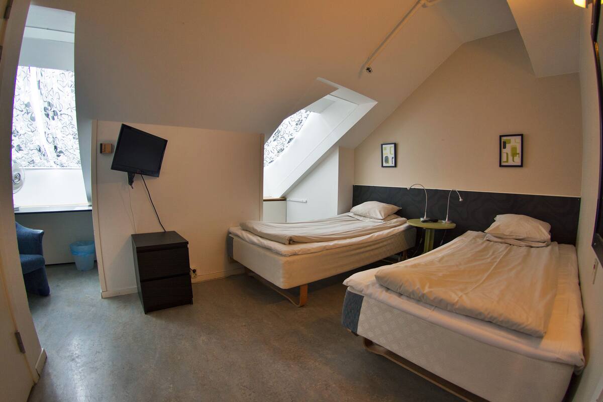 Une chambre à coucher avec un lit, une télévision, un bureau et une fenêtre.