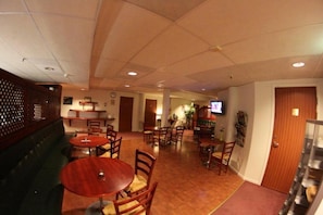 A restaurant with wooden tables and chairs, a bar area, and a television screen.