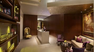 A modern lobby with a reception desk, seating area, and a wall with a large artwork.