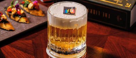 Un verre de bière sur une table en bois, avec, en arrière-plan, un livre intitulé « L’arc-en-ciel de la gravité ».