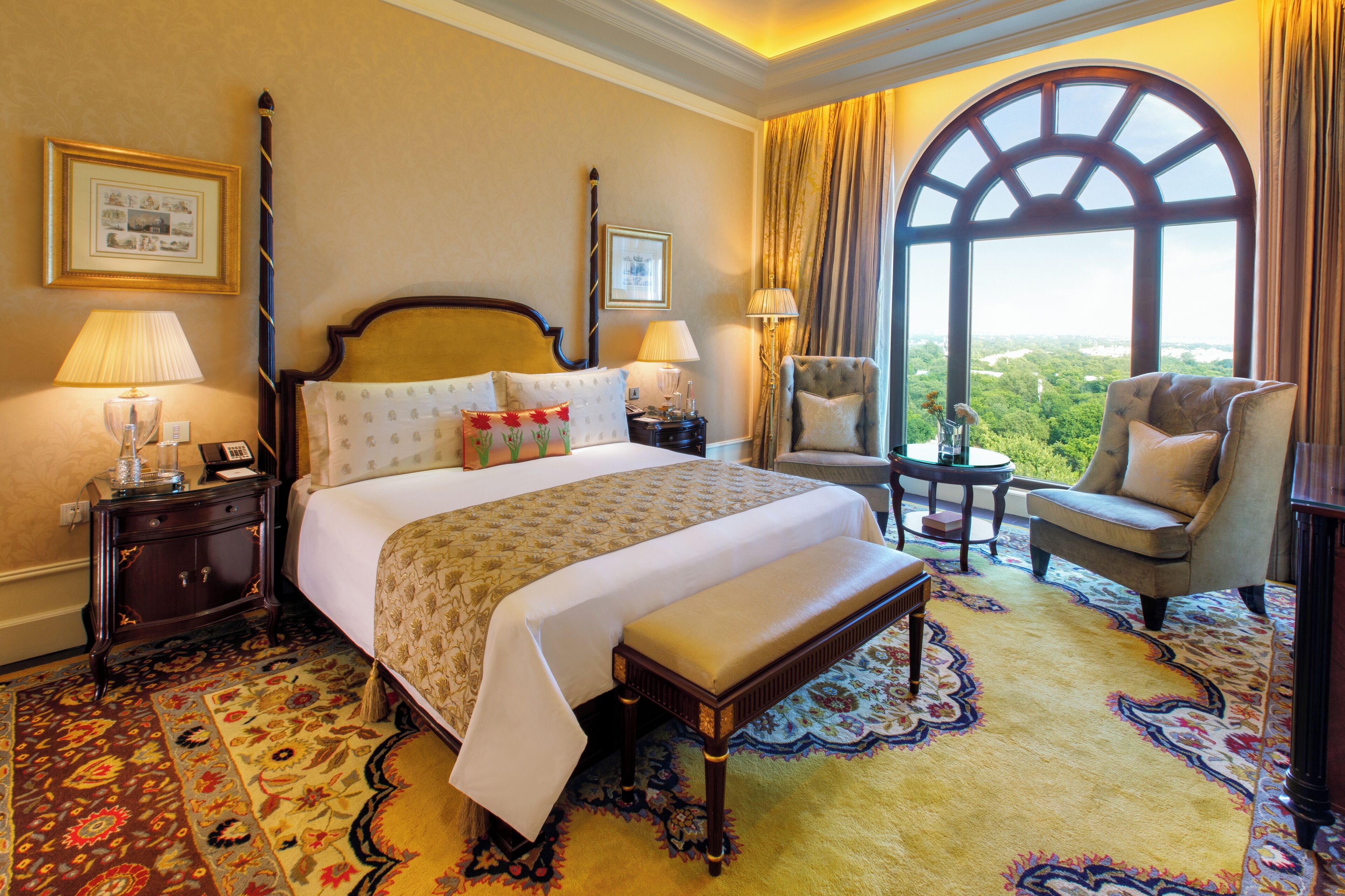 Ein Hotelzimmer mit einem großen Bett, einer Bank, zwei Sesseln, Blick ins Freie und einem großen Fenster.