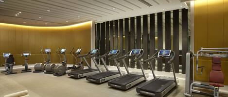A fitness center with treadmills, elliptical machines, and exercise balls.