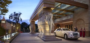Imponente ingresso con una grande statua, una Rolls Royce e un vialetto ben illuminato.