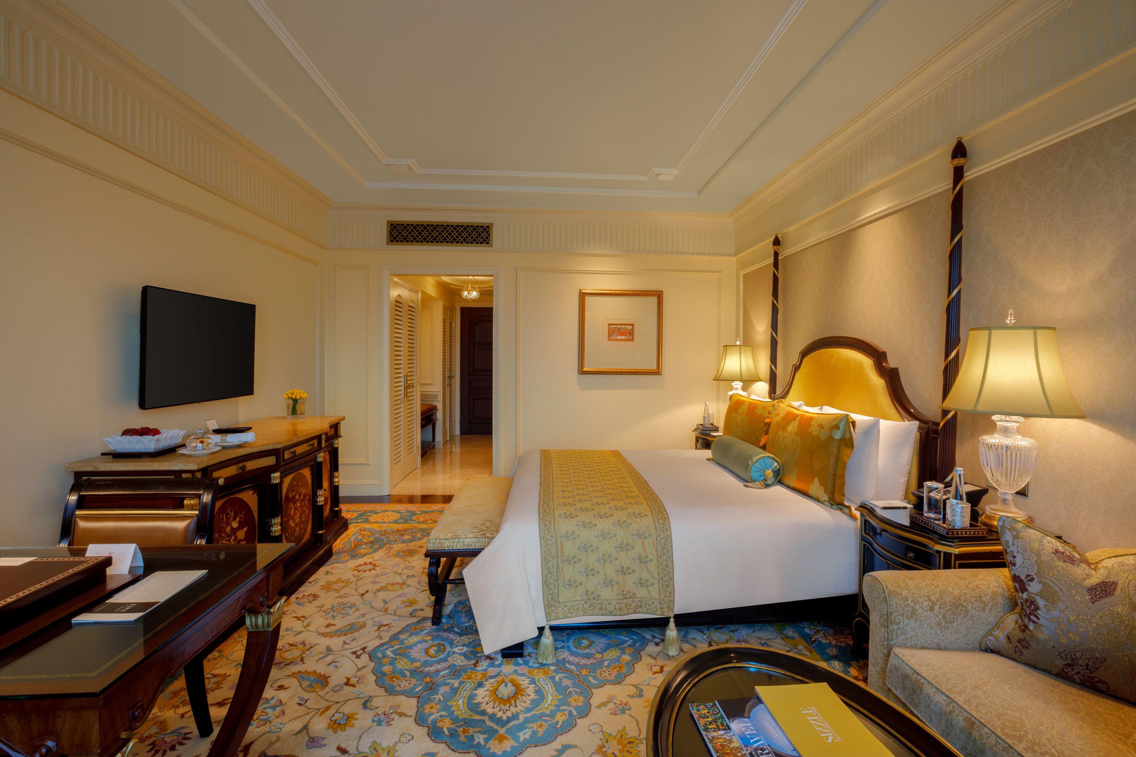 A hotel room with a bed, a desk, a television, and a sofa.