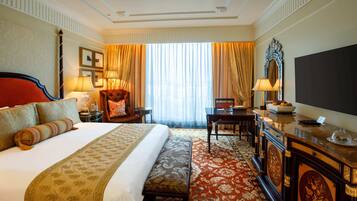 Une chambre d’hôtel avec un grand lit, un bureau avec un ordinateur, une chaise, une télévision et une fenêtre avec des rideaux.