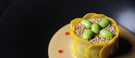 A dessert on a black plate with a creamy sauce and small red dots.