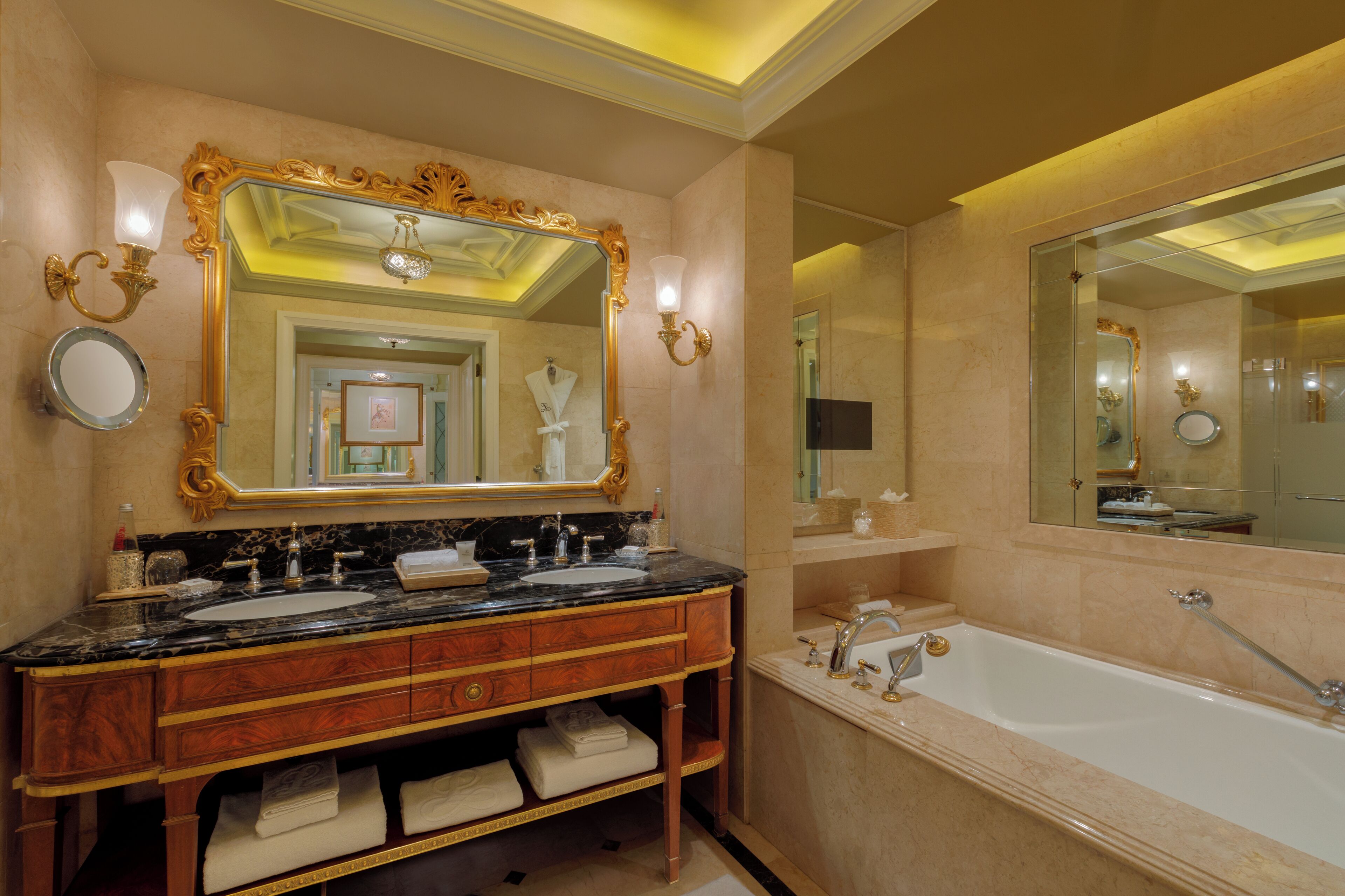 A luxurious bathroom with a double sink vanity, a large mirror, a bathtub, and a shower area.