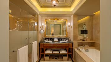 A luxurious bathroom with a double sink vanity, a large mirror, and a separate bathtub.