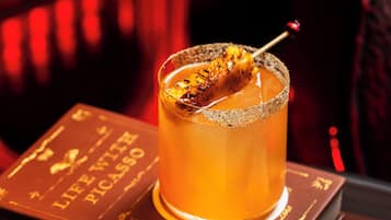 A cocktail on a book titled "The Library Exclusive Cocktails" with a menu card beside it.