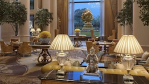 A luxurious lobby with ornate chandeliers, plush seating, and a large window offering a view of a garden. - The Leela Palace New Delhi (New Delhi)