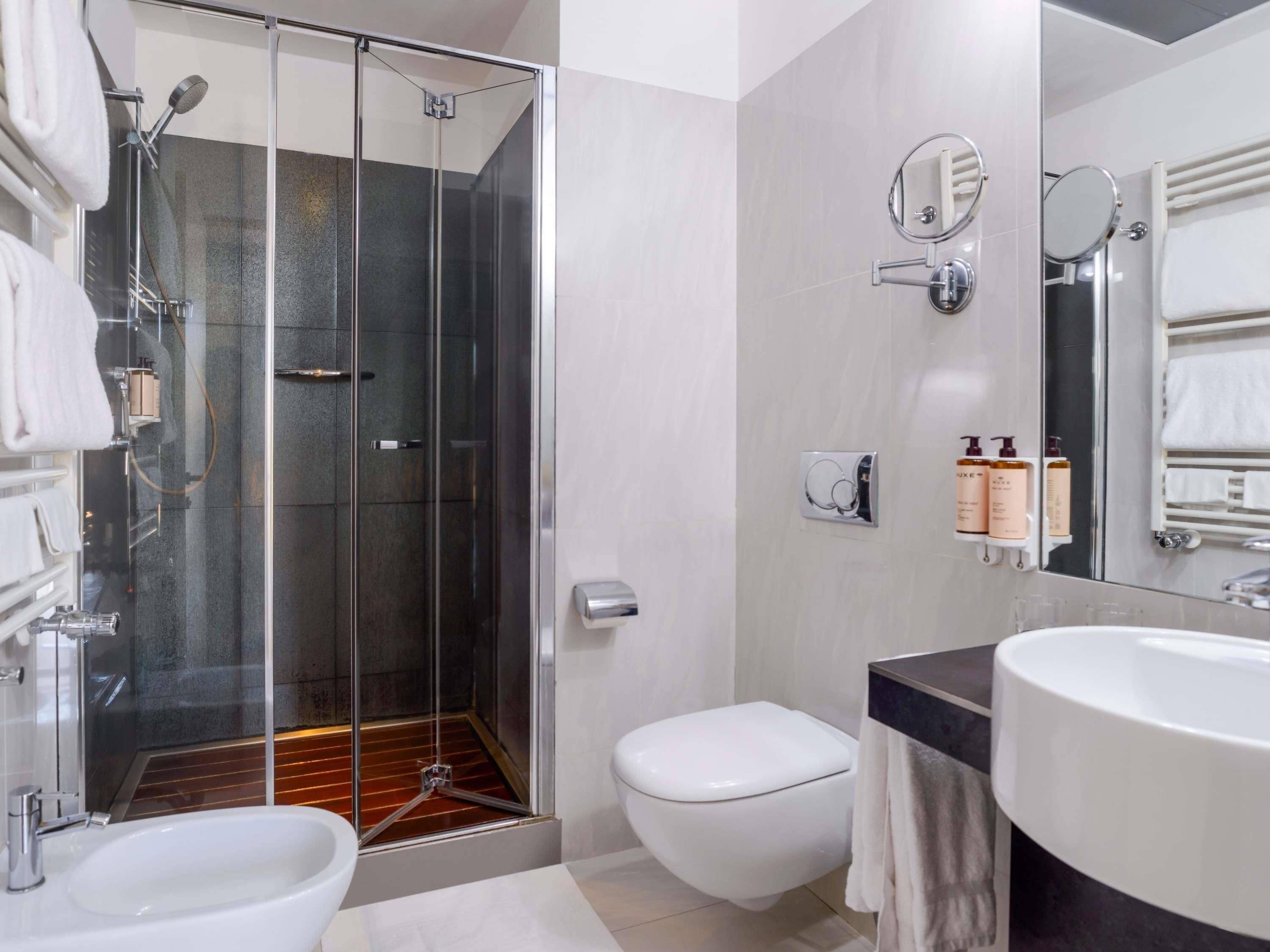 Un baño moderno con ducha acristalada, inodoro blanco, lavamanos y espejo.