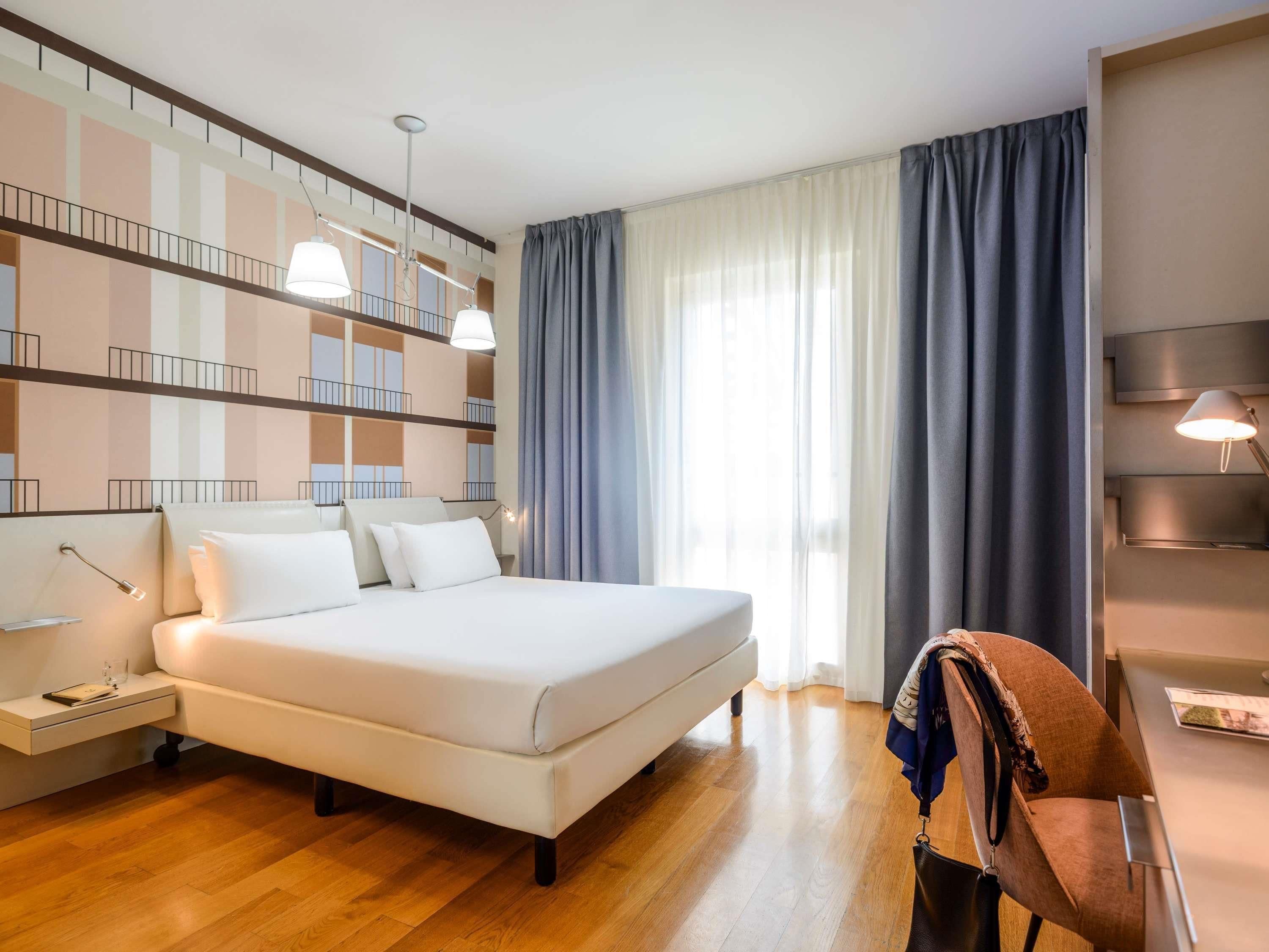 A modern hotel room with a large bed, bedside tables, a desk, and a chair.
