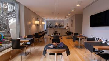 Een moderne hotelentree met een bar, houten vloeren en een groot raam met uitzicht op een trap.