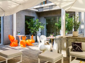 An outdoor seating area with modern furniture, potted plants, and a view of the building's exterior. - Mercure Milano Solari (Milan)