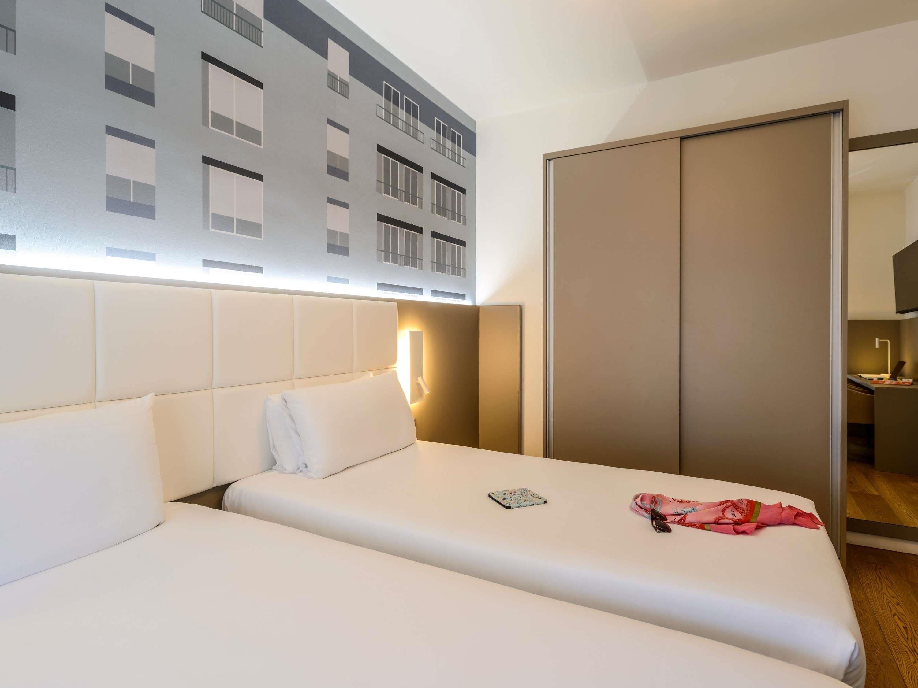A hotel room with a bed, a bedside table, a lamp, and a wardrobe.