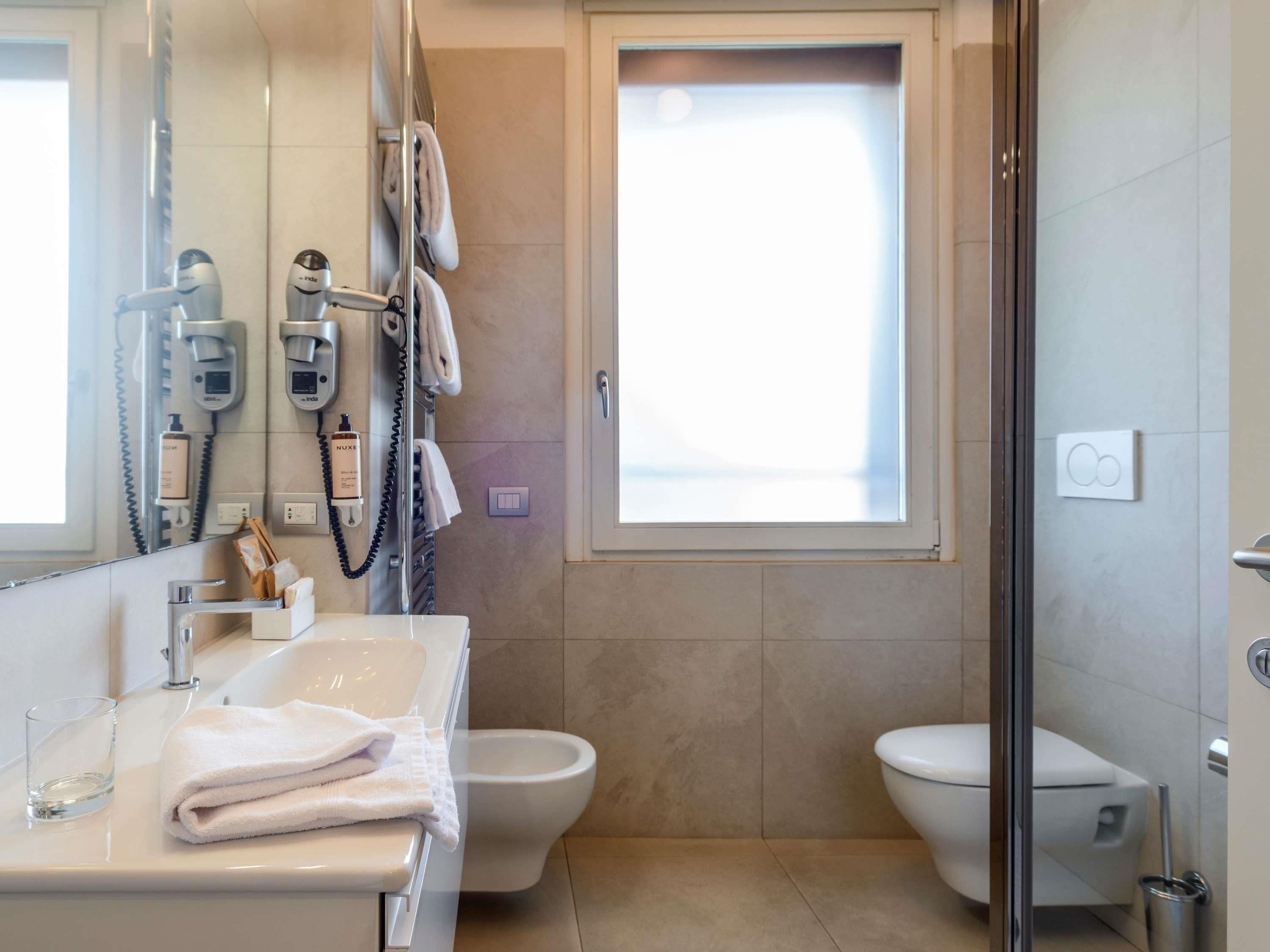 Een moderne badkamer met een douchecabine van glas, een toilet en een wastafel met spiegel.