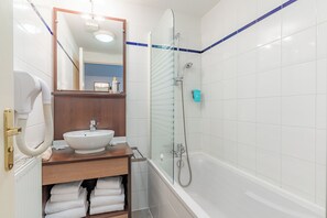 Un baño con lavamanos blanco, espejo, cabina de ducha de vidrio y zona de ducha con azulejos azules.