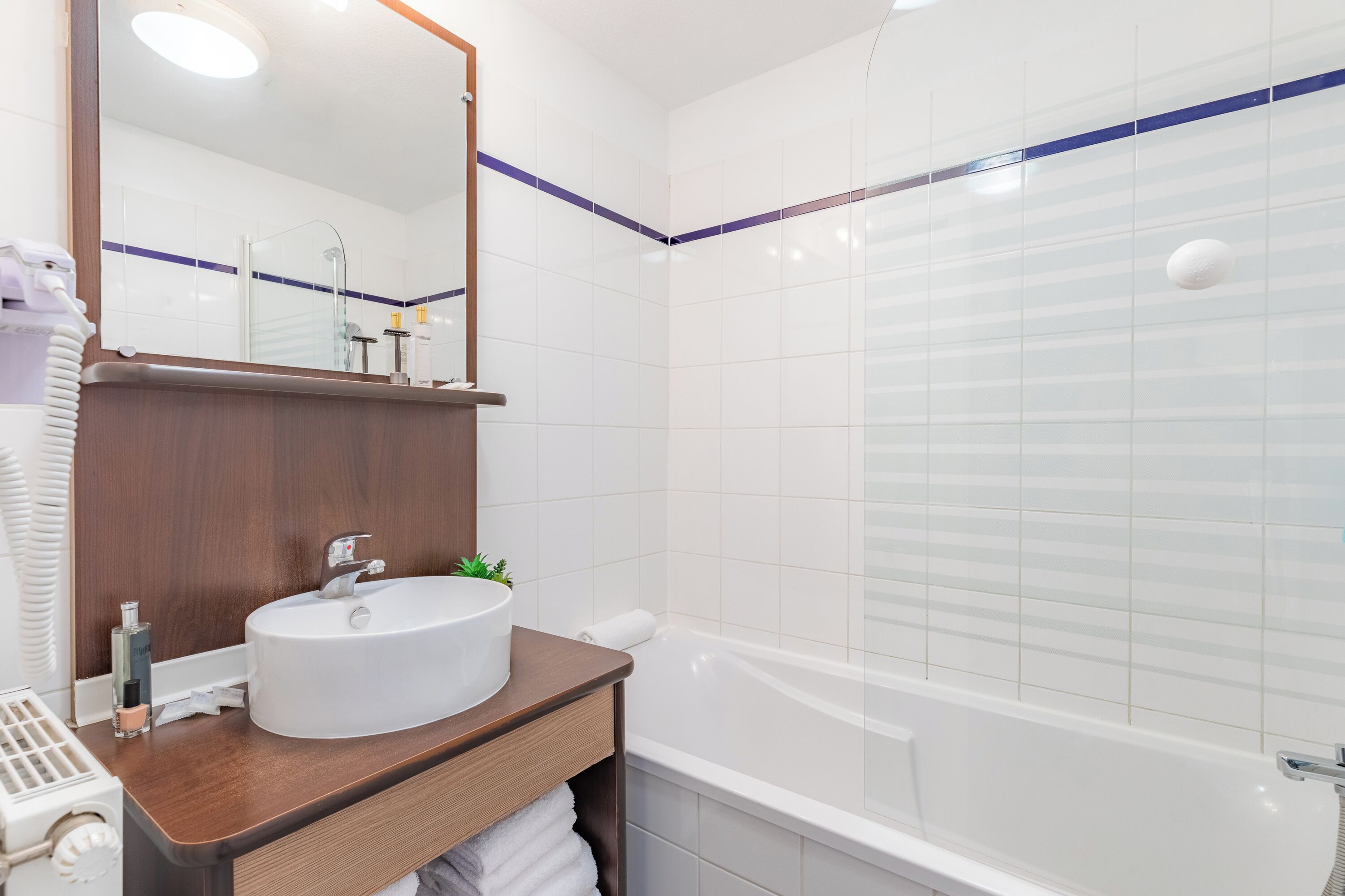 Une salle de bain moderne avec un lavabo blanc, un miroir et une baignoire.