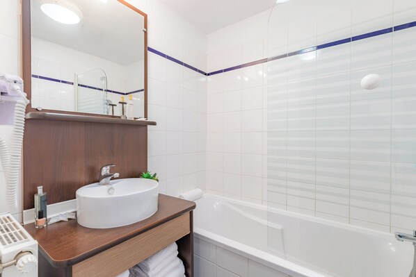 A modern bathroom with a white sink, mirror, and bathtub.