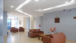 A spacious lobby with leather sofas, a coffee table, and a vase of flowers. - Robinhood Inn (Accra)