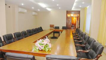 A conference room with a long table, black leather chairs, and a floral centerpiece.