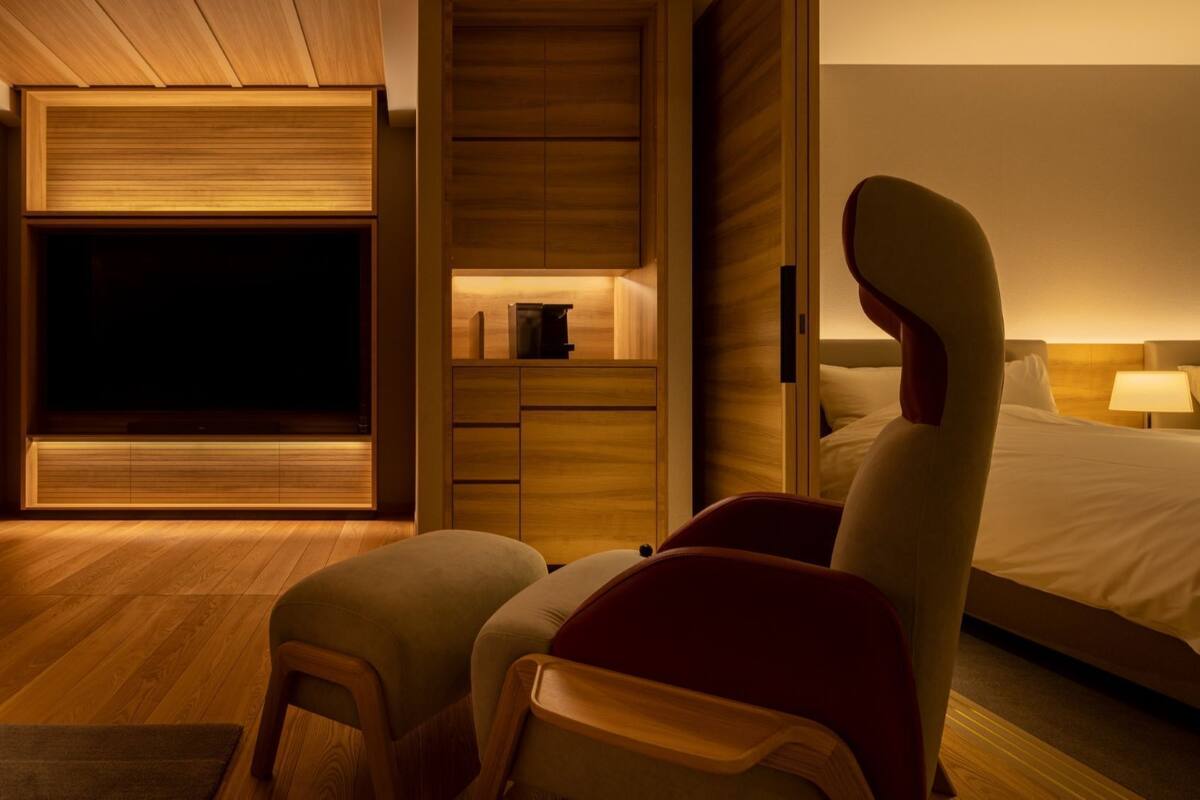 A hotel room with a bed, a desk, and two chairs.