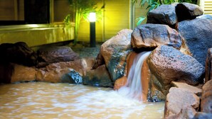 A rock formation with a small waterfall in a garden area. - Arima Onsen Kinzan (Kobe)