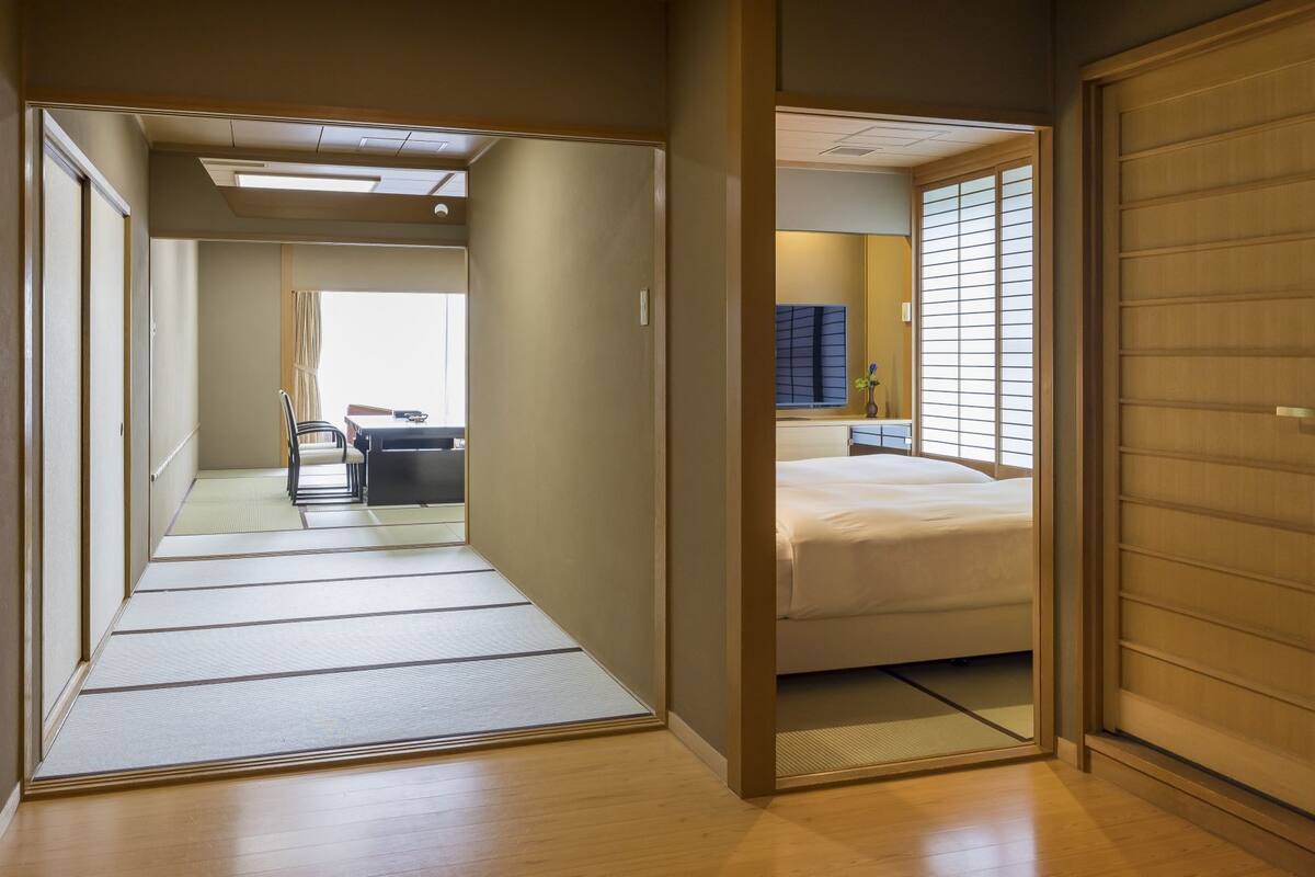 A traditional Japanese room with tatami flooring, a bed, a desk, and a sliding door.