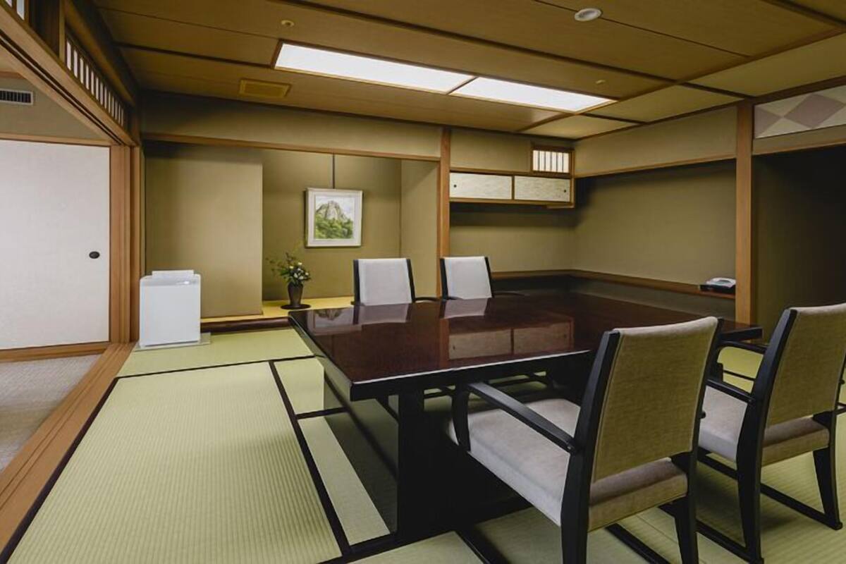 A conference room with a wooden table, chairs, tatami mats, a whiteboard, and a small plant.