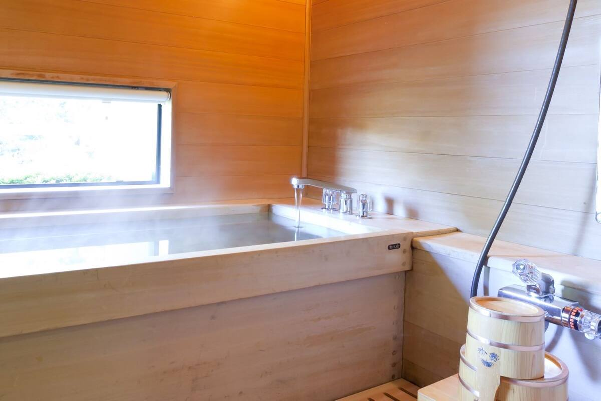 A wooden interior with a large bathtub, a window, and a water filtration system.