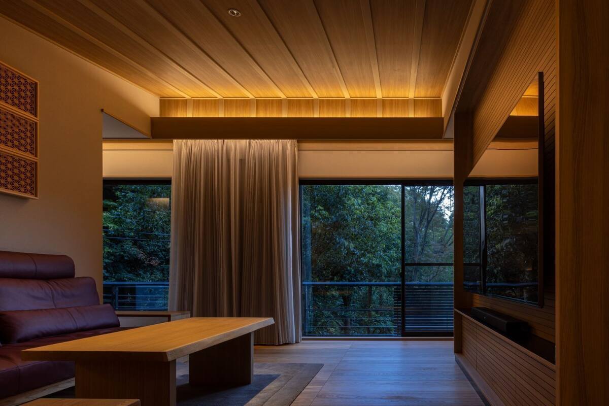 A modern living room with a sofa, a coffee table, and a large window with curtains.