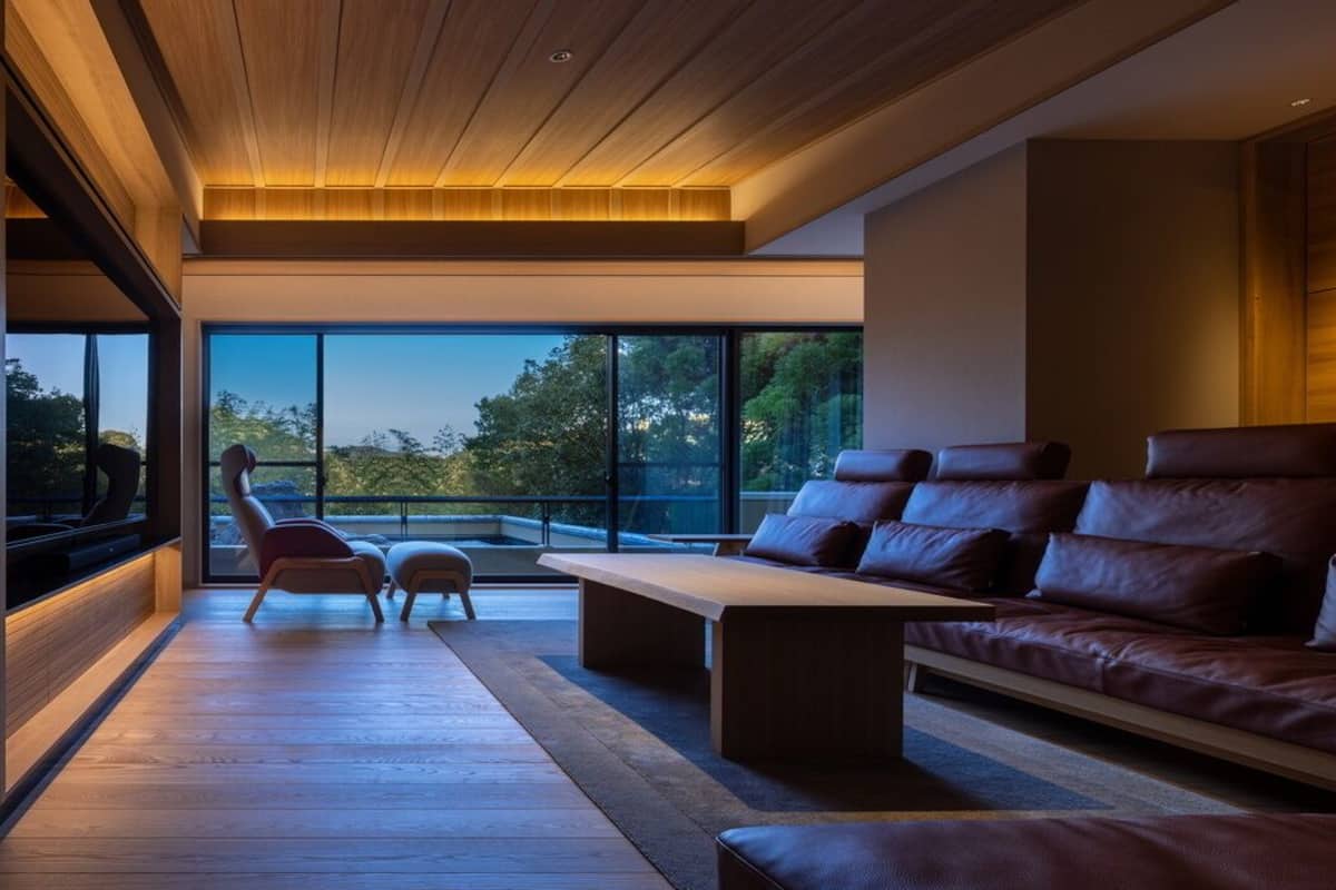 A modern interior with a leather sofa, wooden coffee table, and a view through large windows.