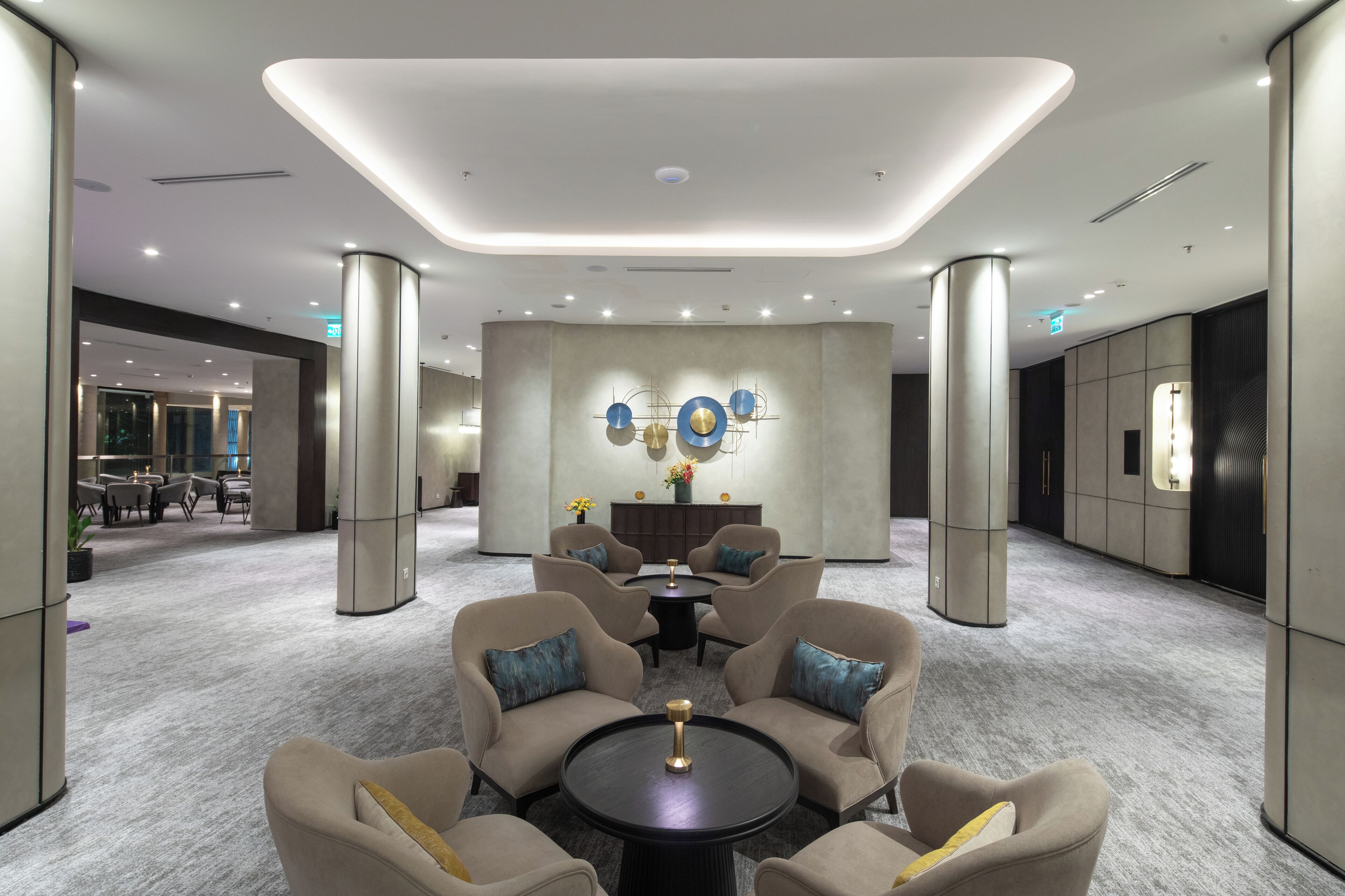 A modern lobby with a central seating area, a decorative wall, and a reception desk.
