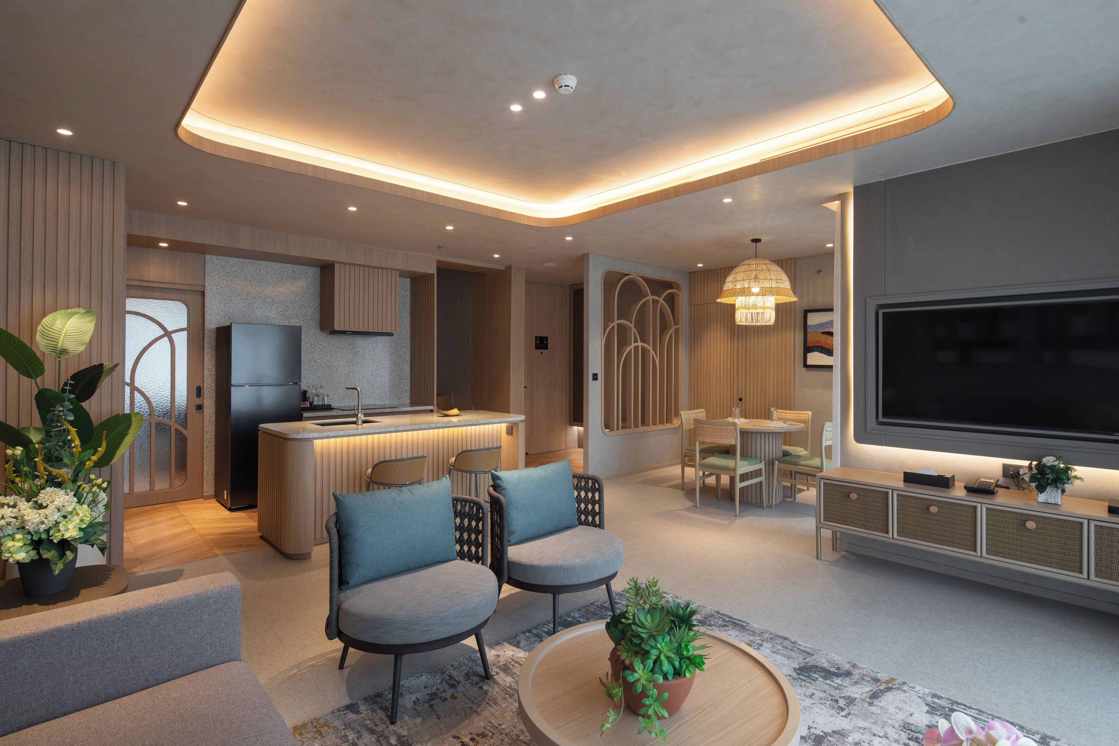 Una sala de estar moderna con un televisor de pantalla plana, asientos cómodos, una zona de cocina y un comedor.