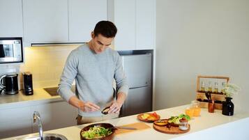 A modern kitchen with white cabinets, a stainless steel sink, a microwave, and a refrigerator.