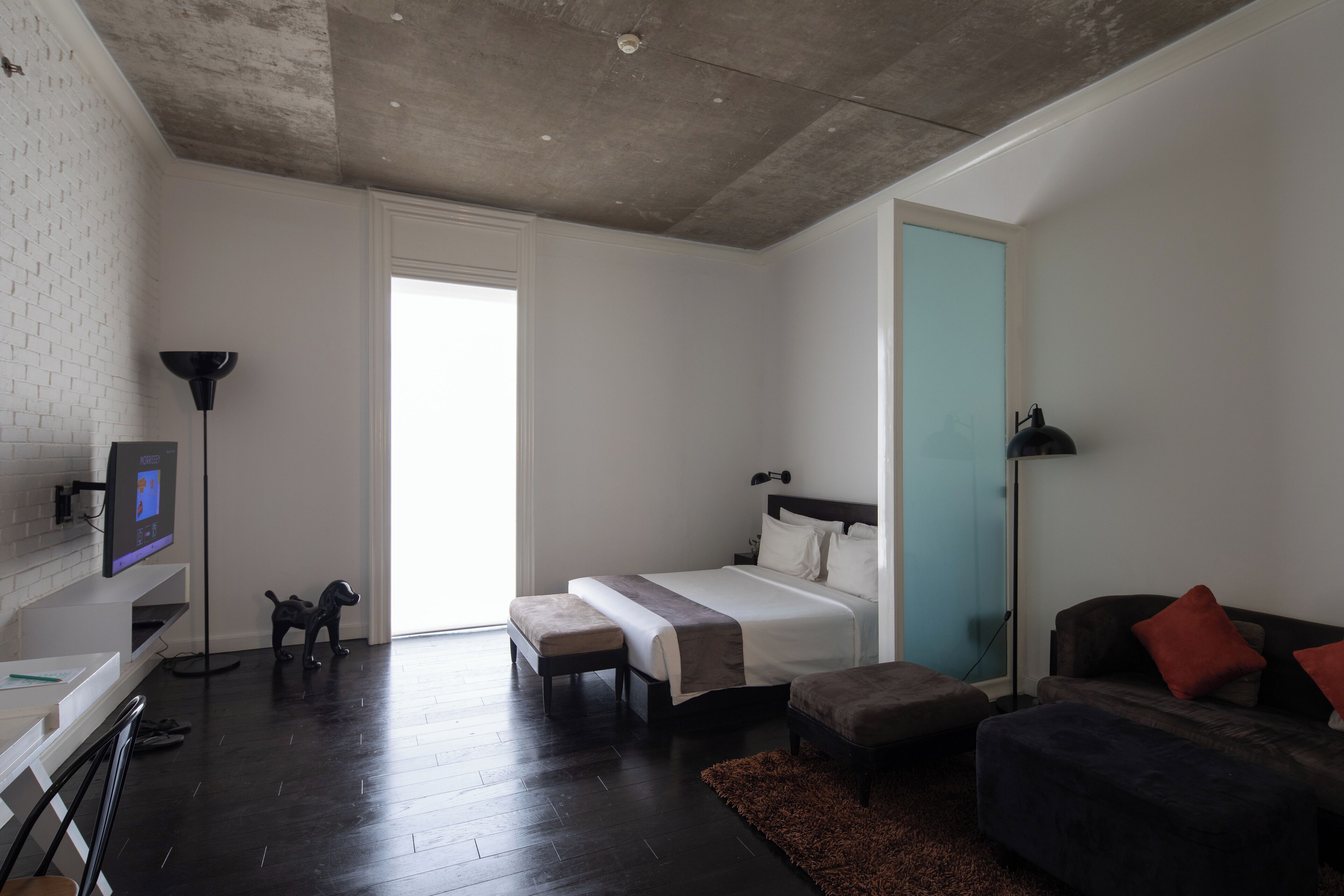 A modern bedroom with a bed, a desk, a chair, a sofa, and a TV.