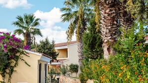 A pathway leading to a building with a tiled roof, surrounded by lush greenery and flowering plants. - Sentido Tirreno Resort (Orosei)