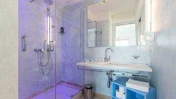 A modern bathroom with a glass-enclosed shower, a white sink, and a blue vanity.