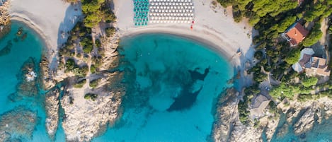 Perto da praia, areia branca, espreguiçadeiras, guarda-sóis 