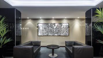 Eine moderne Lobby mit zwei Ledersofas, einem runden Couchtisch in der Mitte und einem großen, abstrakten Kunstwerk an der Wand.