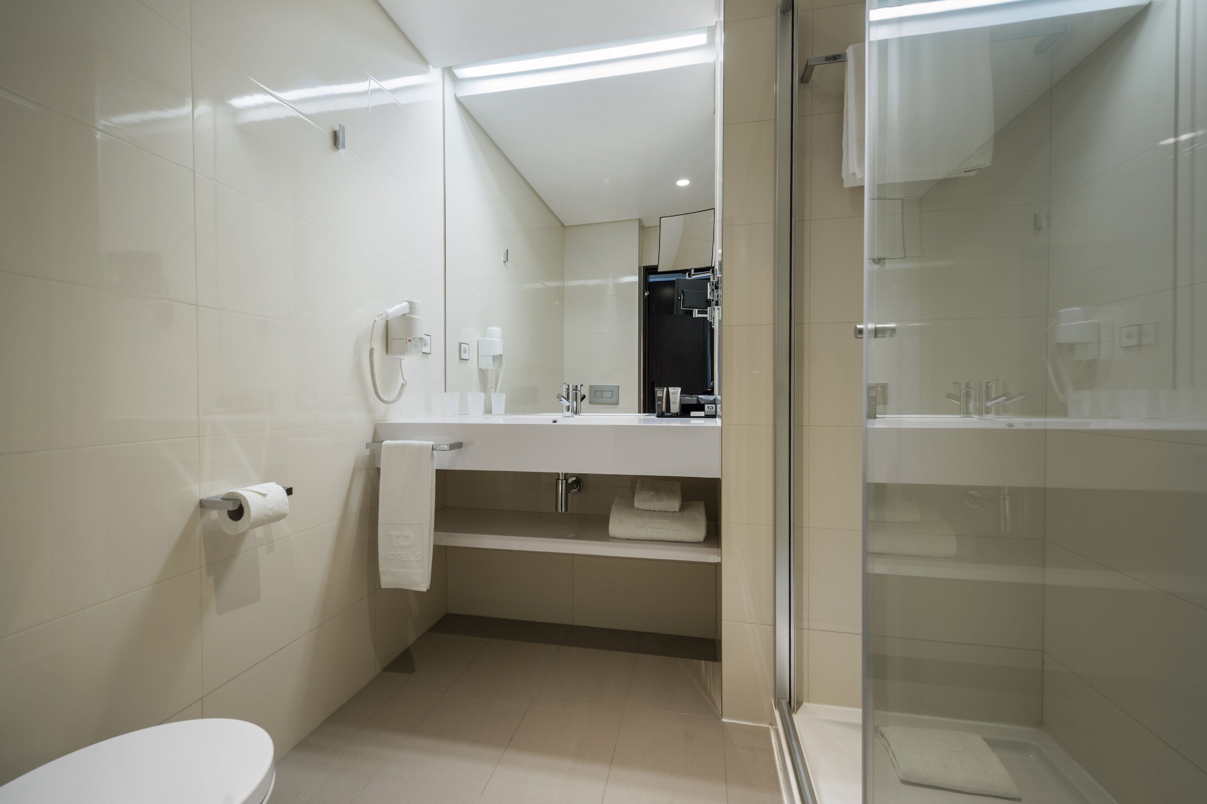 Un baño moderno con inodoro, lavabo y zona de ducha.