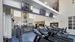 A gym with treadmills, weight machines, and a TV screen. - Hotel Trópico (Luanda)