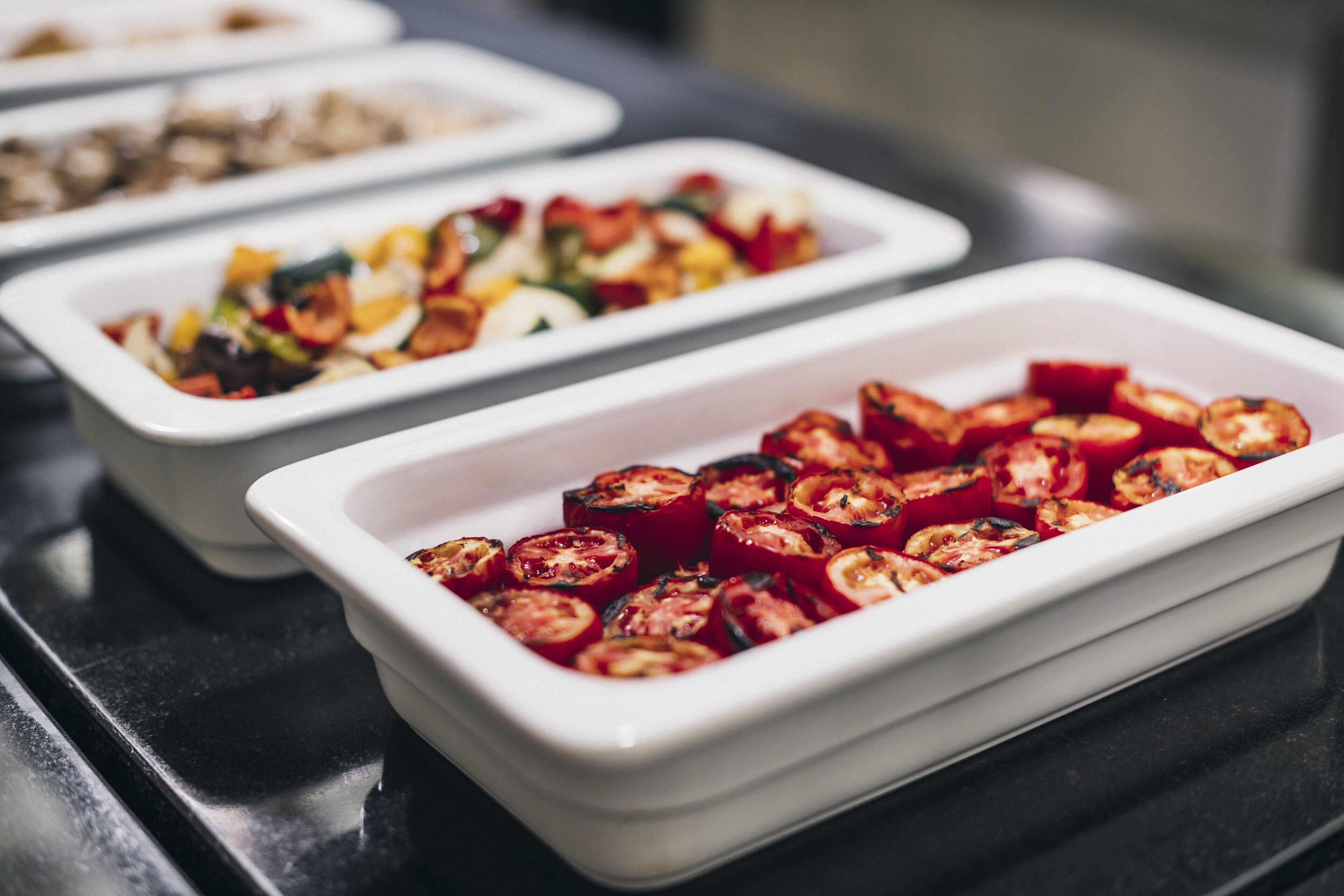 A buffet with various dishes, including roasted vegetables and salads.