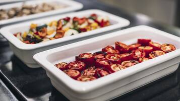 A buffet with various dishes, including roasted vegetables and salads.