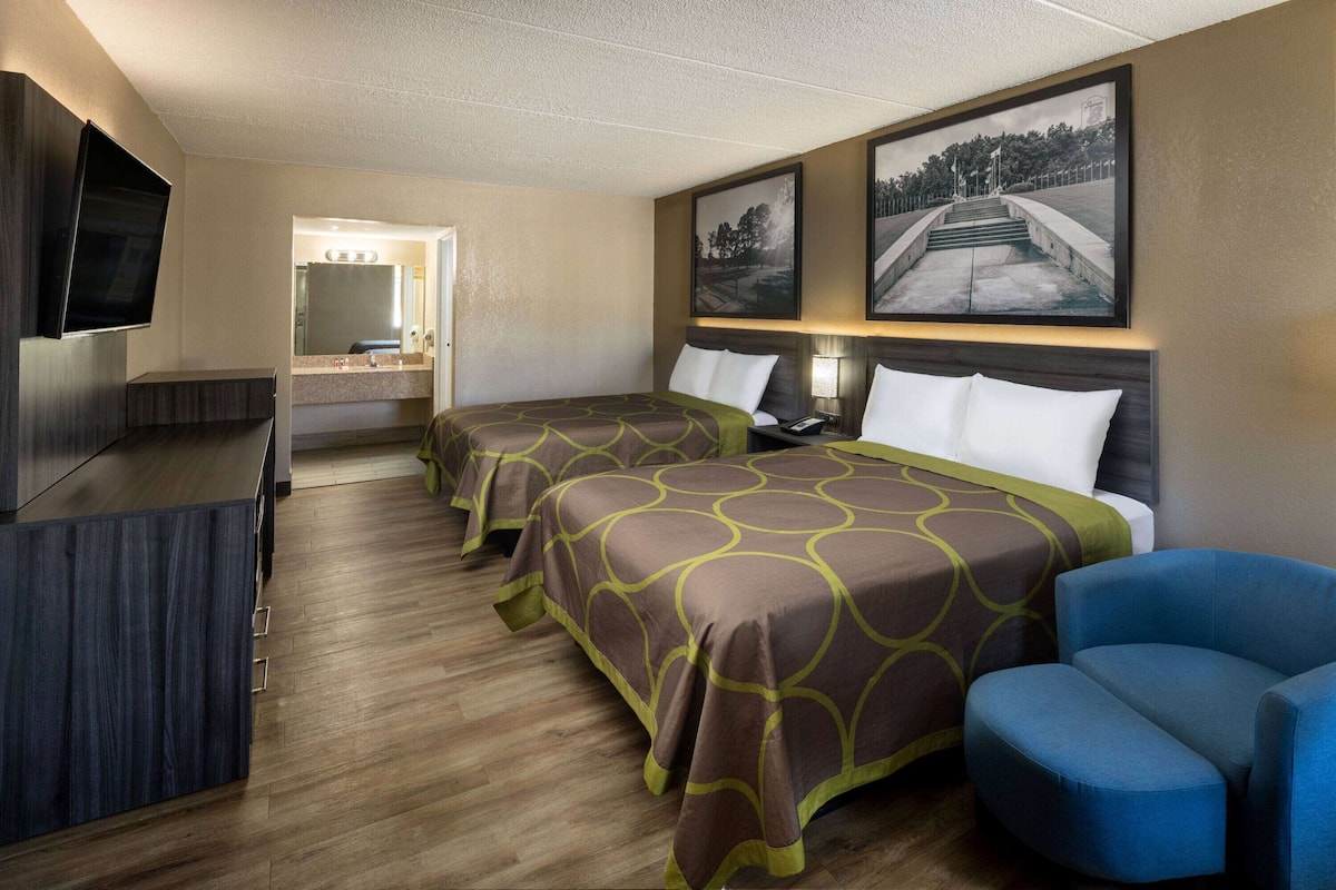 Une chambre d’hôtel avec deux lits, un bureau, une télévision et une chaise.