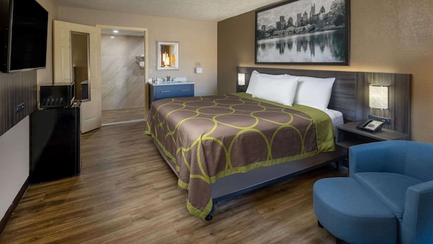 Een hotelkamer met een bed, een bureau, een stoel, een televisie en een schilderij aan de muur.