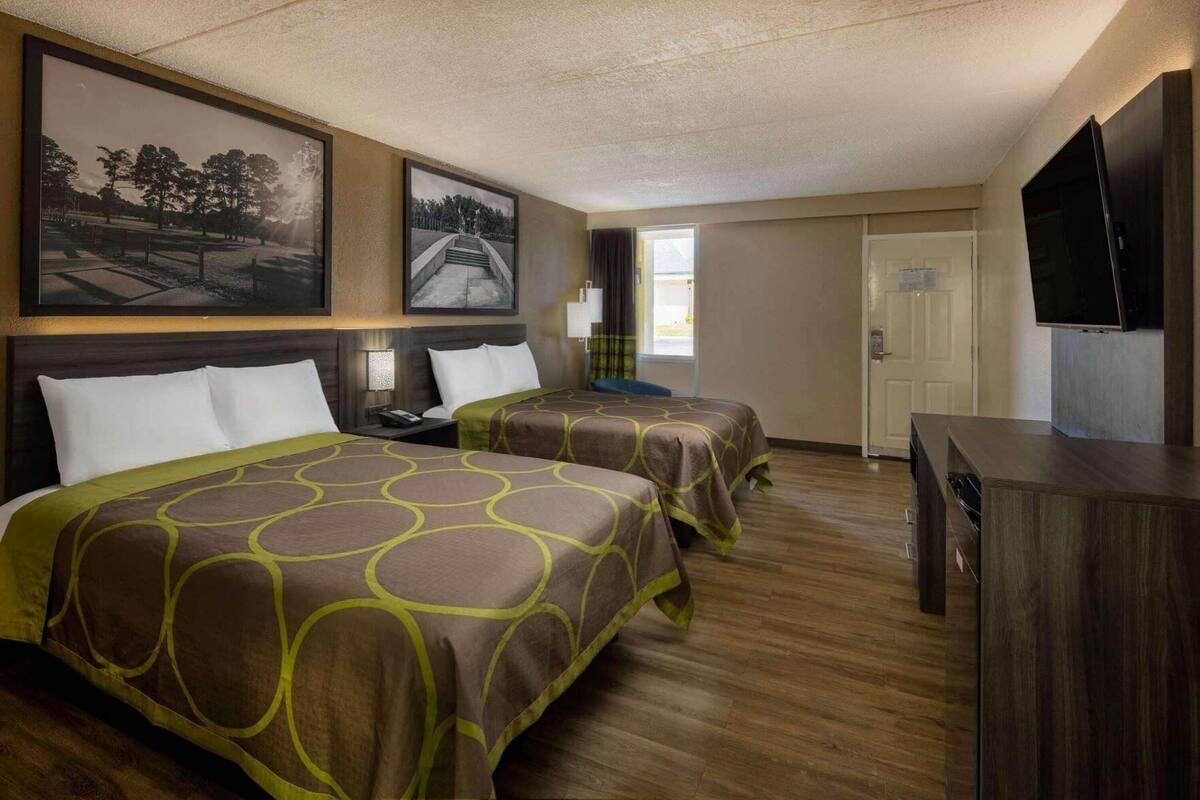 Une chambre d’hôtel avec deux lits, une télévision et des œuvres d’art accrochées aux murs.