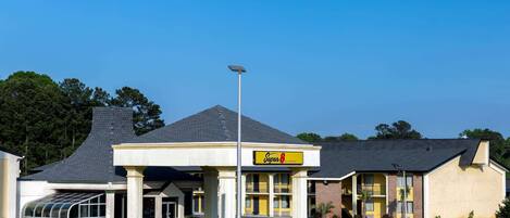 A motel with a yellow and white exterior, a covered entrance, and a solar-powered streetlight.