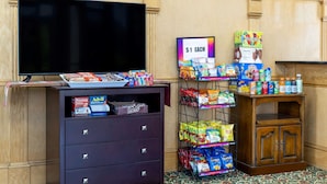 Een etalage met snacks, een bord waarop $1 staat, een televisie en een kast met diverse spullen.