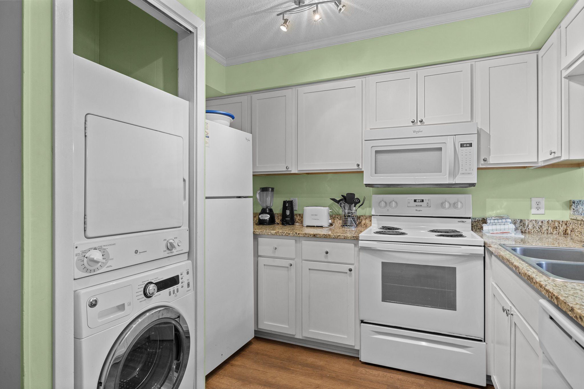 A compact kitchen with a washing machine, microwave, toaster, and stove.